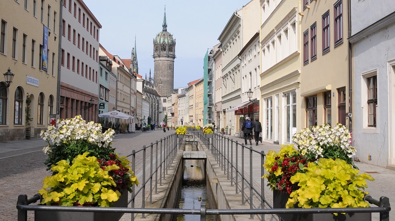 Gatubild från Wittenberg, i mitten av gatan finns en smal kanal med staket och blomsterarrangemang.
